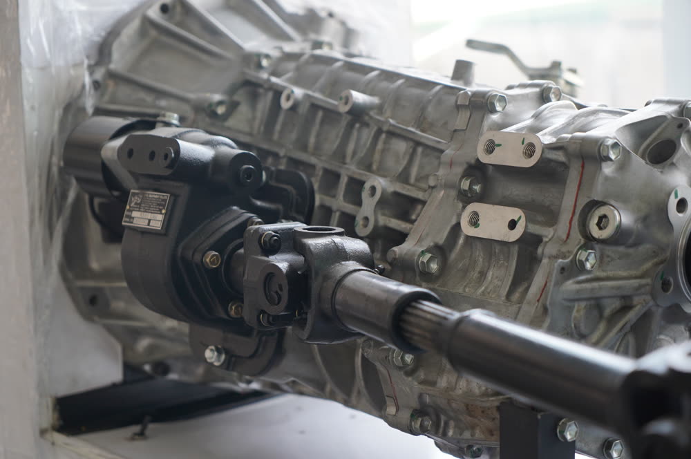 Gearbox-mounted PTO bolted to the side of a truck gearbox, with a drive shaft coming off it