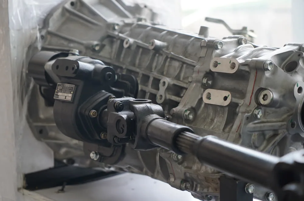 Gearbox-mounted PTO bolted to the side of a truck gearbox, with a drive shaft coming off it
