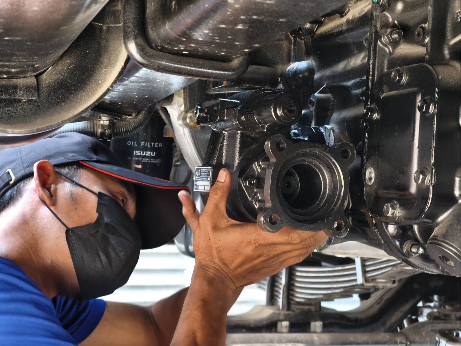 VPS technician checking a PTO and the oil filter under a truck gearbox