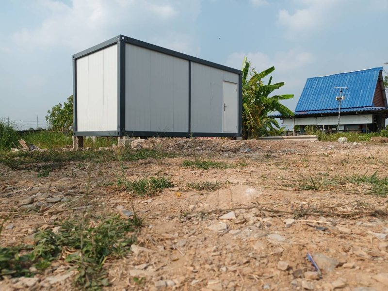Single-unit container office with solar panel on a green field
