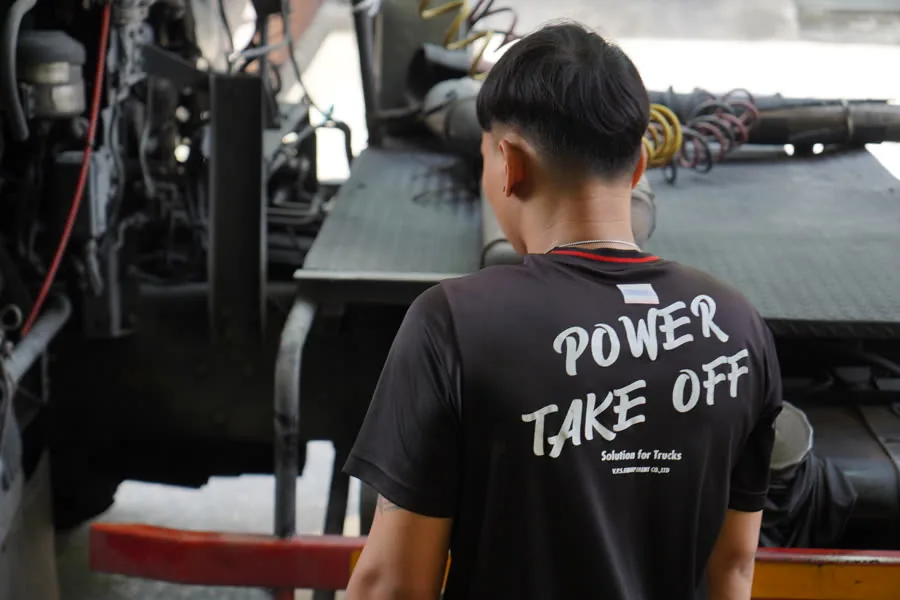 VPS technician at work on a truck gearbox, in a Power Take Off shirt